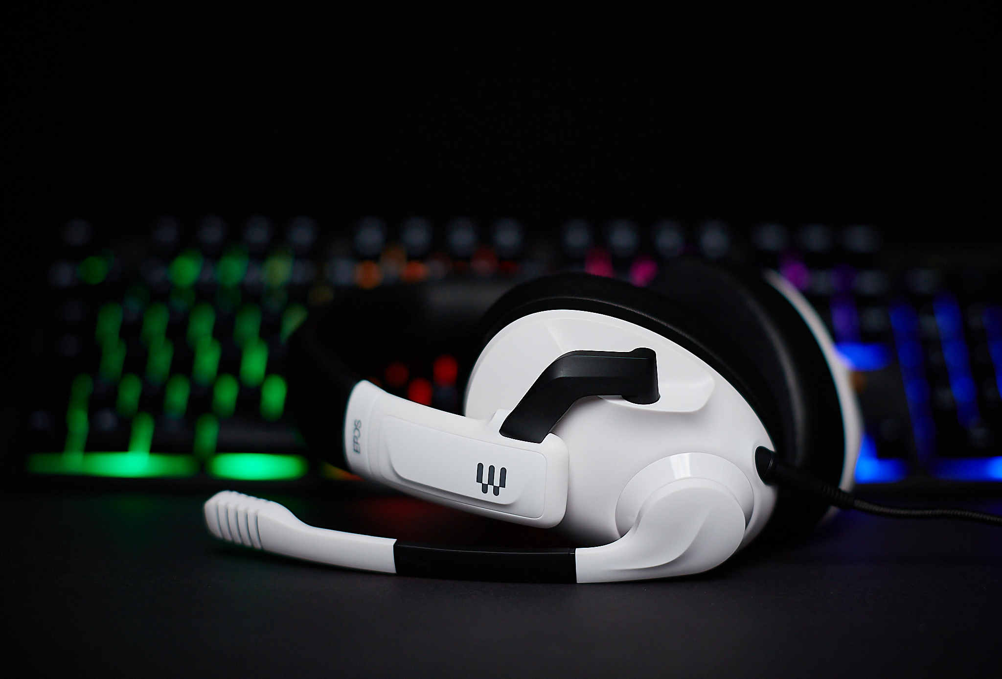 A white and black headset lying in front of a keyboard.