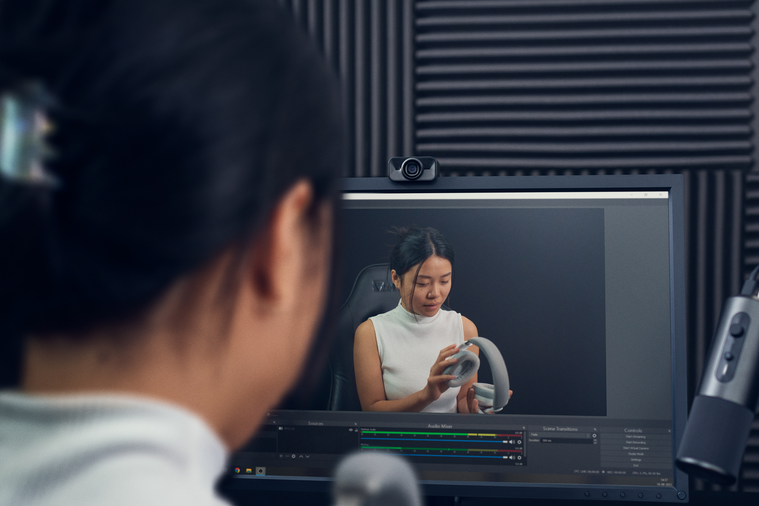 A woman looking at a computer monitor with the S6 webcam on top of it.