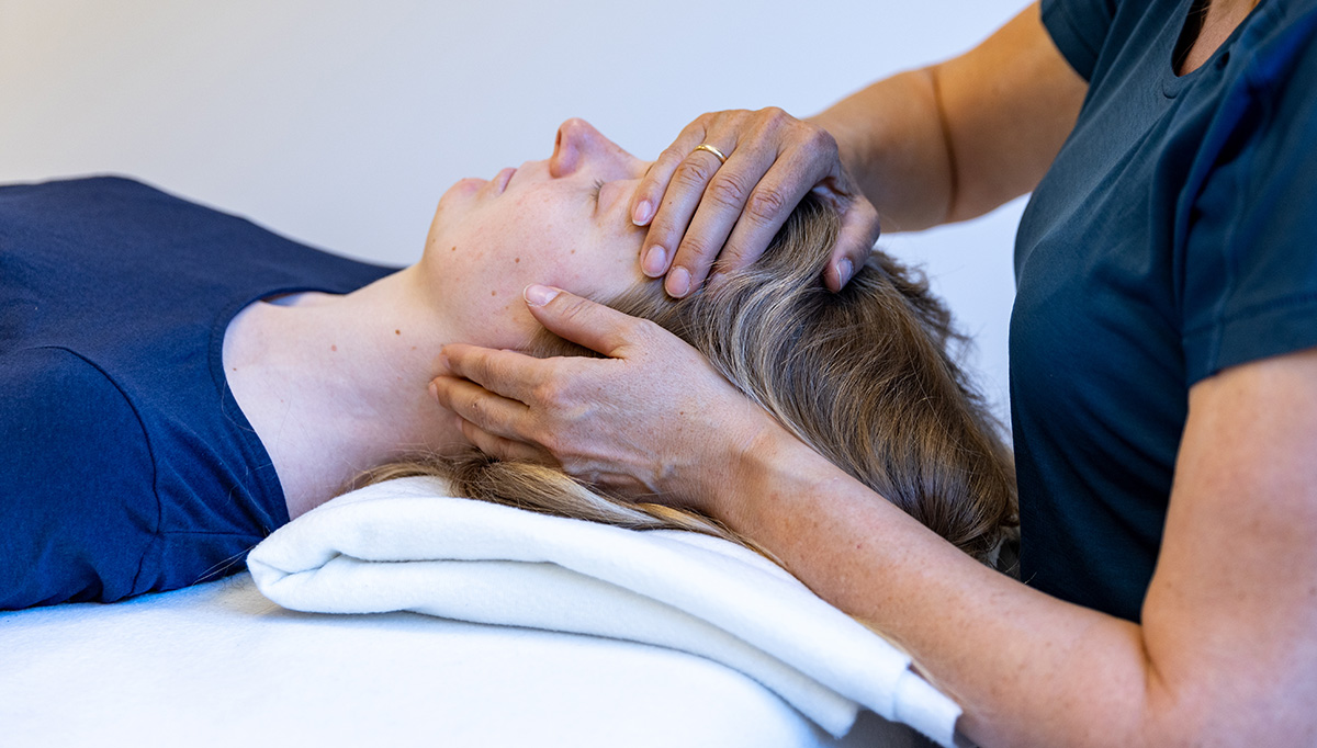 A woman touching anohter woman's forehead.