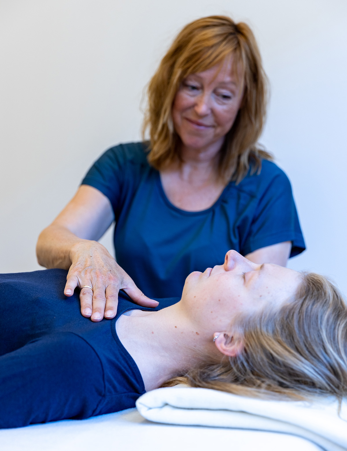 A woman looking at another woman lying down.