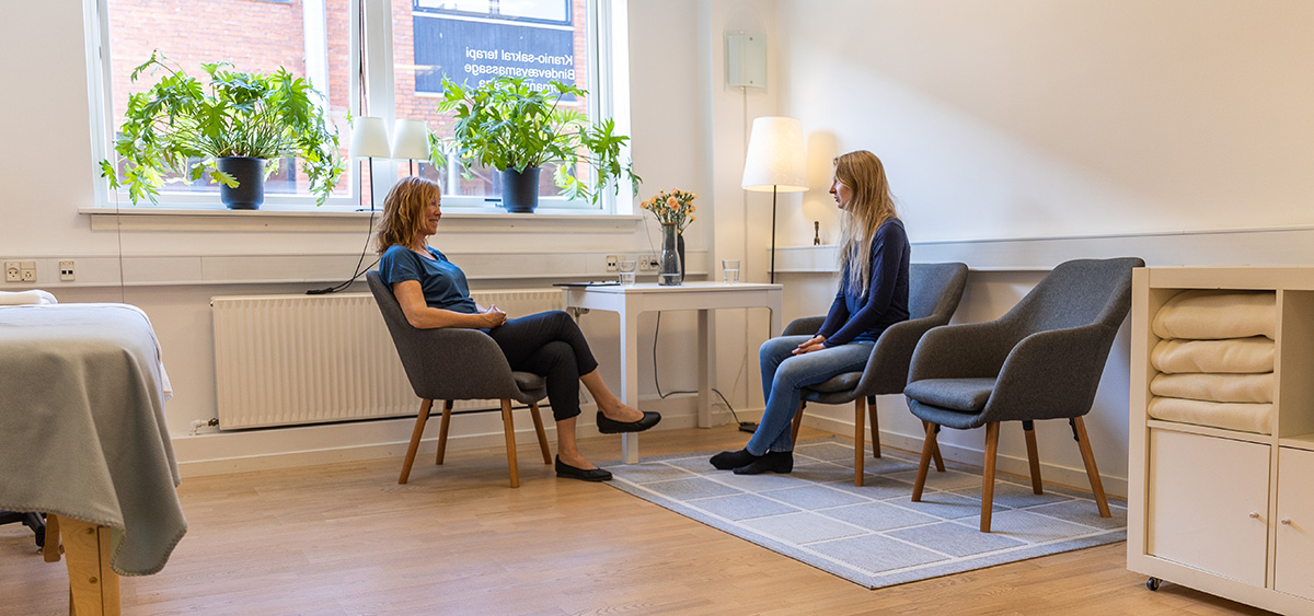 Two women sitting down and talking to each other.