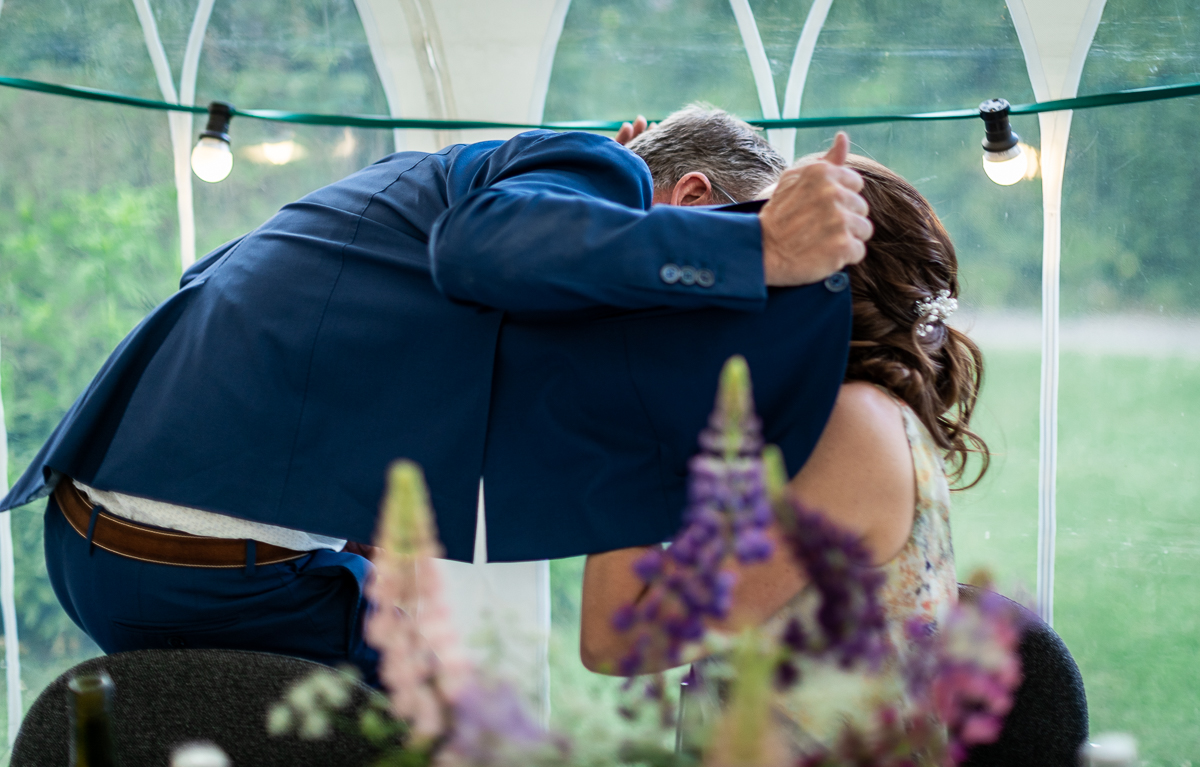 The bride and groom hiding that they are kissing.