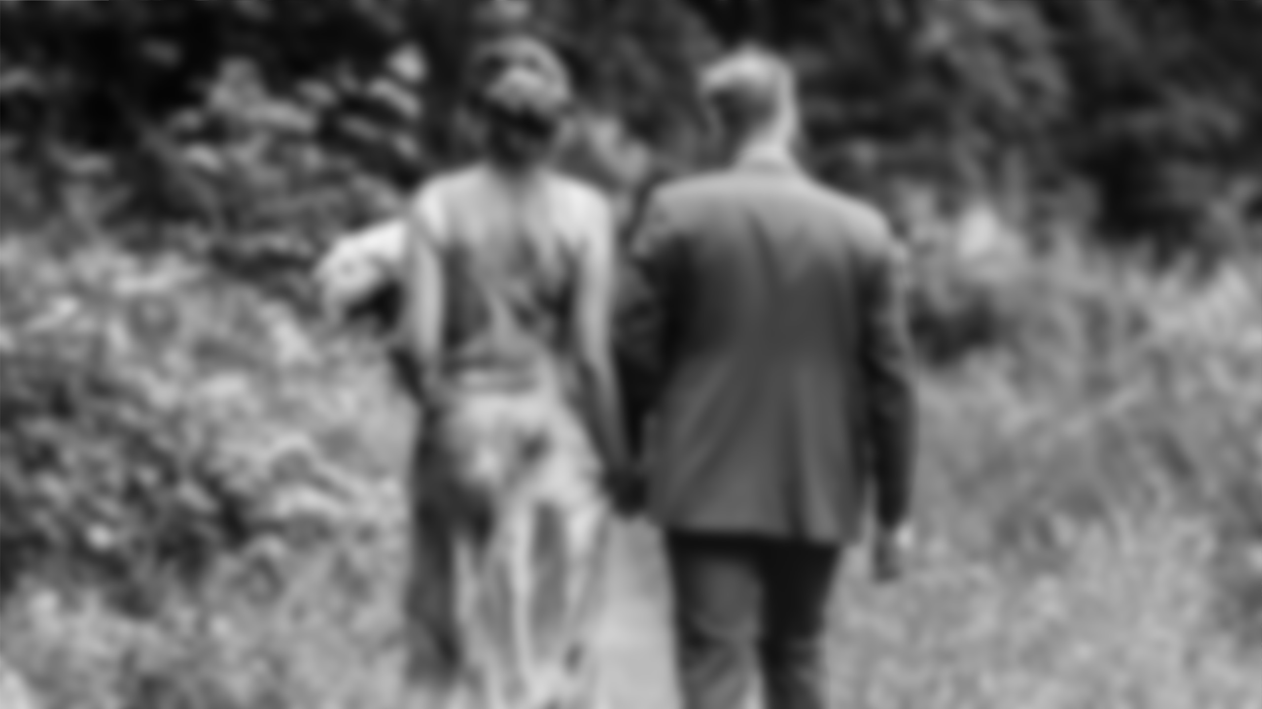 A bride and a groom walking away in nature.