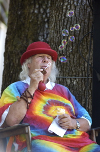 Wavy Gravy, inventor of the propeller cap, blowing soap bubbles.