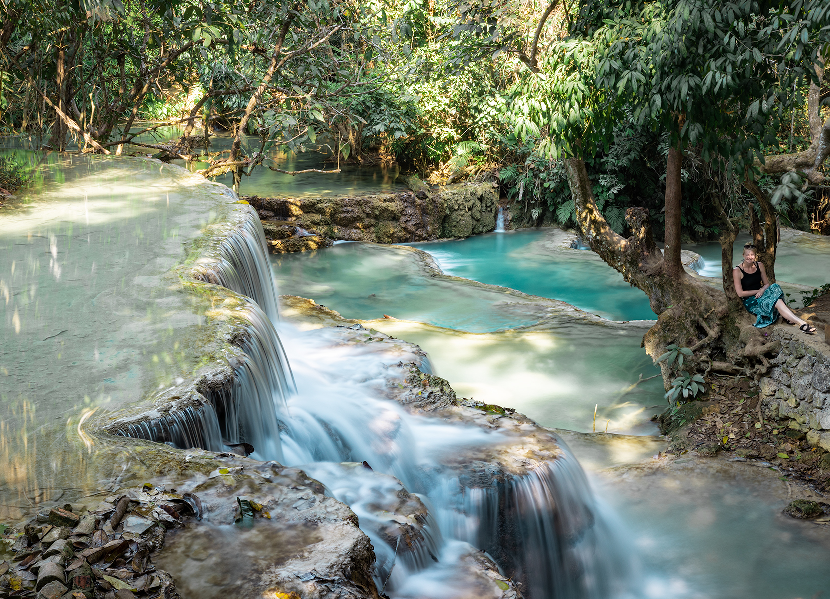 Young woman sitting next to a waterfall.