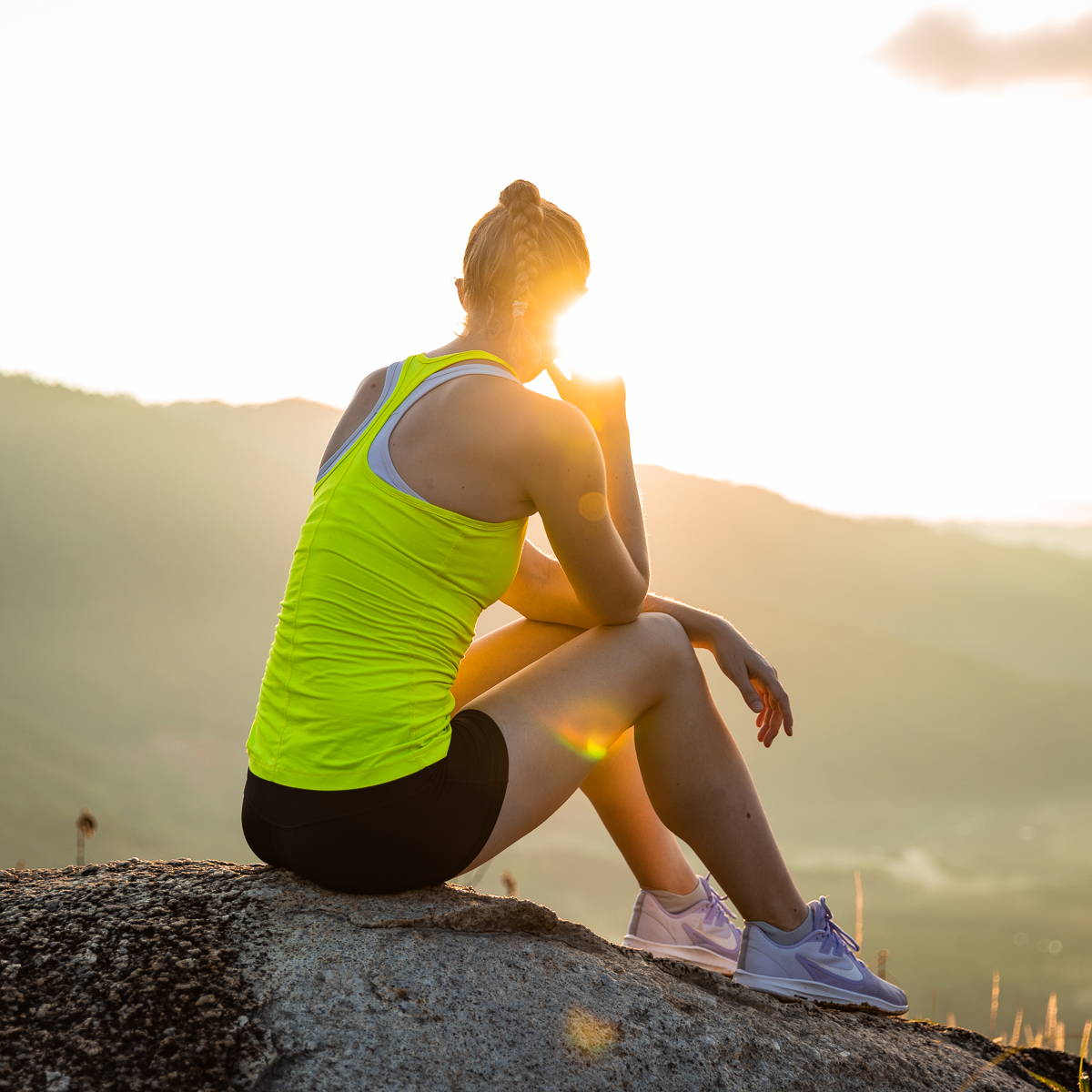 Woman sitting on a rock at sunrise.