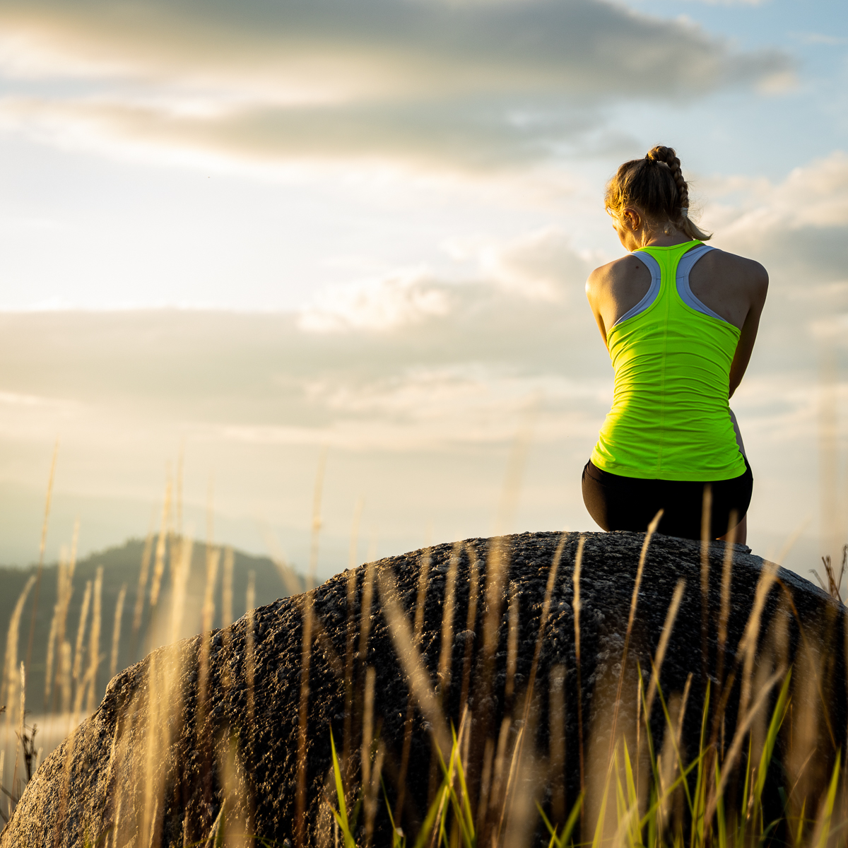 Woman sitting on a rock at sunrise.