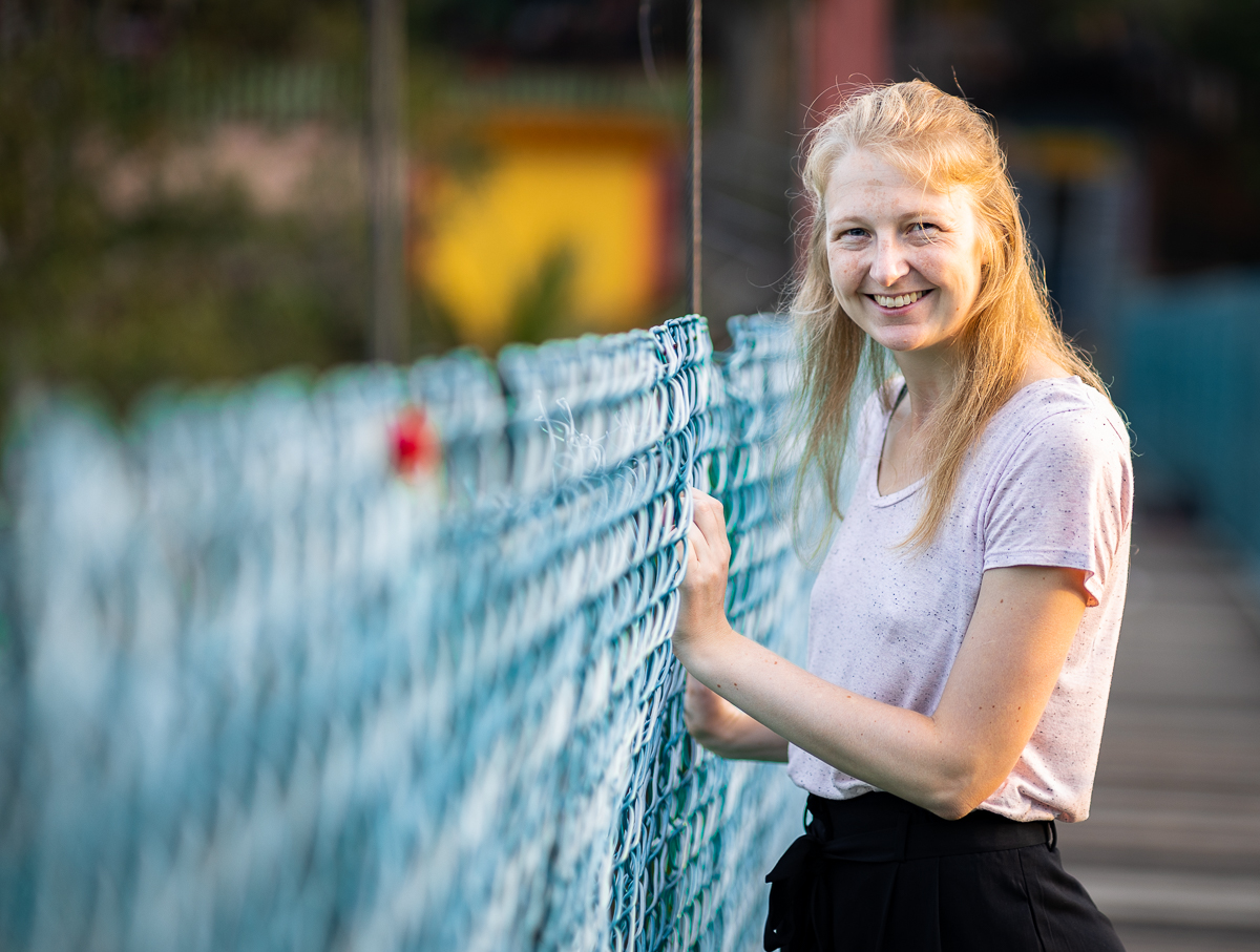 A woman smiling on a bridge.