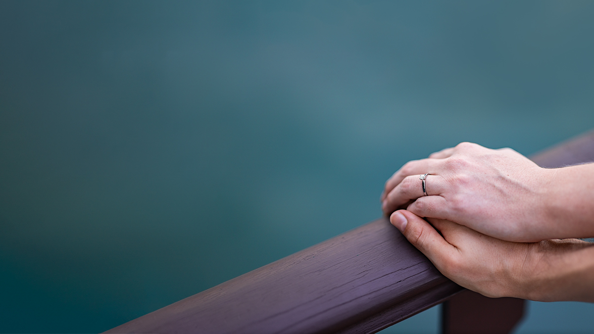 Two hands resting on a railing.